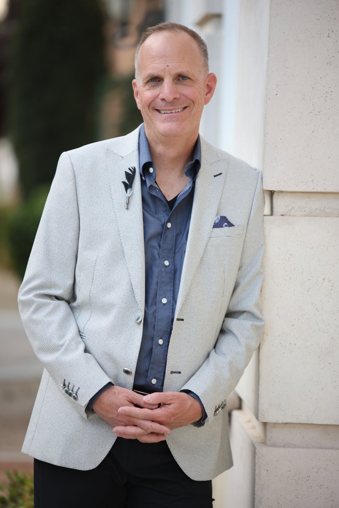 Dr. David Stella, DC, standing outdoors in a light jacket, hands gently clasped
